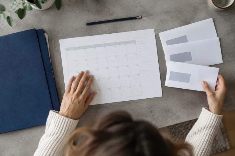 Zwei Hände ordnen Terminunterlagen neben einem aufgeschlagenen Kalender